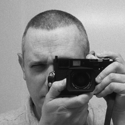 Chad Remesch holding a rangefinder camera to his eye.